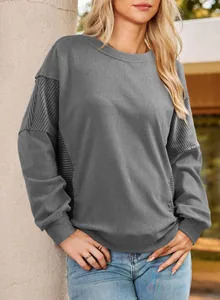 Close-up detail of a grey long-sleeve sweatshirt featuring stylish striped patchwork