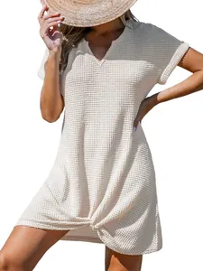 Dettaglio ravvicinato di un abito estivo beige in maglia a nido d'ape con nodo a V