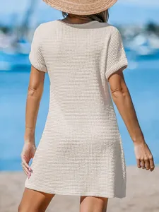 Vista posteriore di un copricostume beige in maglia a nido d'ape per donna in spiaggia