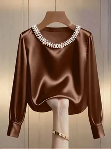 Close-up of elegant satin blouse with pearl-embellished neckline and smooth texture