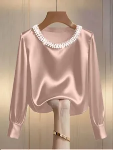 Detail of French style satin blouse featuring a pearl-embellished round neckline