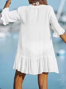 Back view detail of white V-neck beach dress with elegant ruffle hem and sleeves.