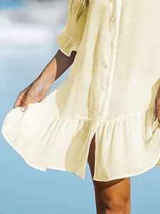 Close-up view of the ruffled hem and button details on a solid color beach cover-up dress