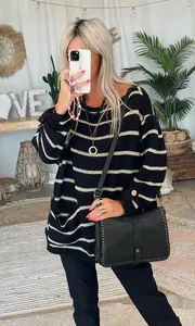 Mannequin portant un pull en maille rayé oversize dans un décor intérieur douillet