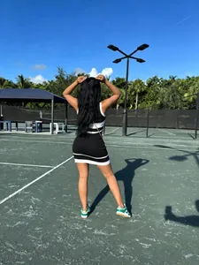 Vista trasera de mujer con vestido corto de punto a rayas blancas y negras en pista de tenis