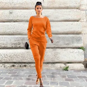 Fashionable model posing in bright orange ribbed knit two-piece sweater and pants set
