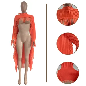 Close-up details of orange knit long fringed sweater showing texture and tassels.