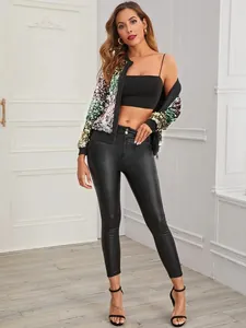 Model draagt een casual kleurrijk damesjasje met lovertjes en zwarte leren broek.