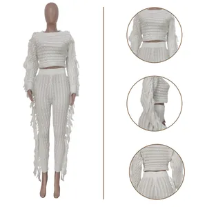 Detail view of white knitted two-piece set with fringe accents and textured weave.