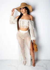 Close-up of white crochet mesh beach two-piece set featuring long fringe and high slit.
