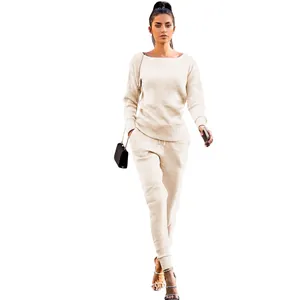 Full body view of a woman wearing a beige ribbed knit two-piece set on white background