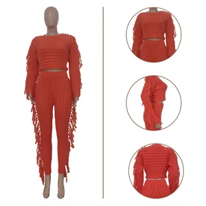 Detail view of women's orange knitted two-piece set with long-sleeve top and fringe trim.