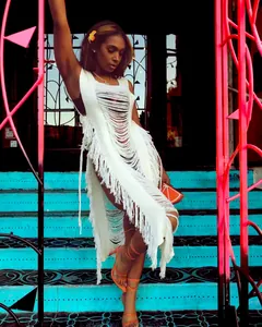 Stylish woman wearing a white knitted fringe beach cover-up dress on cyan steps