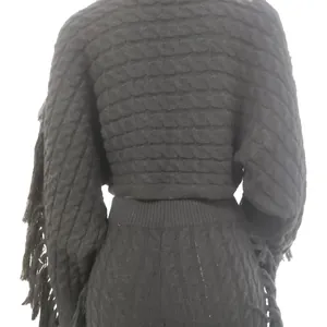 Back view of a black cable-knit sweater and pants set with fringes on the sleeves.