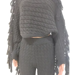 Detailed view of black cable knit sweater featuring long fringe accents on the sleeves