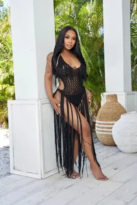 Detail view of black crochet one-piece bodysuit with long fringe trim and hollow knit design