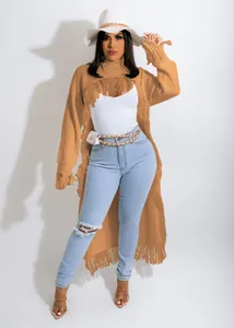 Full view of elegant ochre long tassel knit sweater paired with ripped denim jeans.