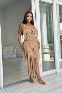 Model wearing a tan crochet one-piece swimsuit with long fringe details for beachwear.
