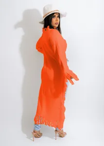 Detailed view of bright orange long fringe knit cardigan with white fedora hat