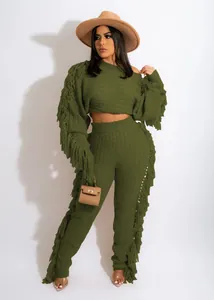 Detail of green knitted two-piece set featuring long fringe tassels and textured fabric
