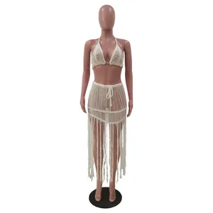 Detail of white crochet mesh two-piece beach set with halter top and tassel skirt.