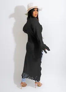 Detailed view of long black knitted sweater with fringe trim and tassel hem