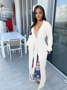 Detailed view of a white long-sleeved fringed cardigan sweater on a model outdoors.