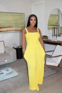 Detailed view of a bright yellow smocked wide-leg jumpsuit worn by a model in a home setting
