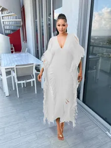 Close-up view of white handmade knitted maxi dress featuring fringe details and V-neckline.