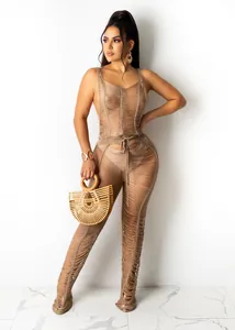 Full-length view of a sexy beige knitted hollow-out jumpsuit with waist tie detail