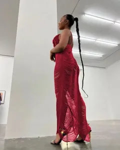 Dettaglio laterale di un abito in maglia rossa senza maniche con lunghe frange e scollo a V