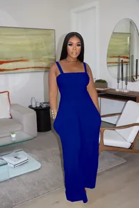 Royal blue sleeveless smocked wide leg jumpsuit for women shown in a modern living room.