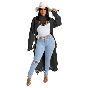Detail view of a stylish black long fringe sweater paired with ripped jeans and a white hat