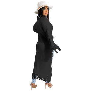Detail view of a black long-sleeved knit cardigan featuring long fringe hem and side trim.