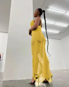 Dettaglio del vestito lungo giallo a maglia con frange, scollo a V e design traforato