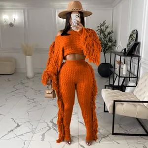 Close-up detail of a vibrant orange knitted long-sleeve two-piece set featuring stylish side fringe