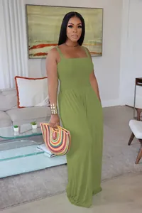 Full-length view of a woman wearing an olive green sleeveless smocked wide-leg jumpsuit.