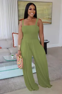 Full-body detail of olive green smocked wide-leg jumpsuit on model in home setting