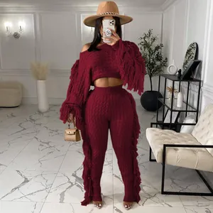 Detail of burgundy two-piece knitted set featuring a long sleeve top and pants with fringe