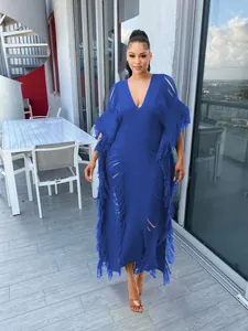 Full-length view of a blue hand-knitted fringed long dress with a deep V-neckline detail