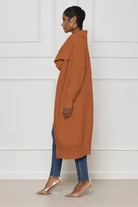 Side view of a long rust-colored oversized knit cardigan worn by a stylish model