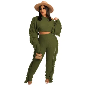Detail view of green knitted two-piece set featuring long fringe on sleeves and pants