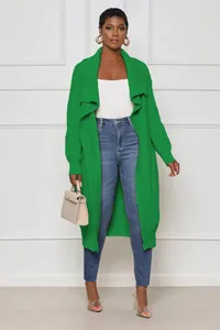 Full view of women's long green knit cardigan styled with jeans and transparent heels