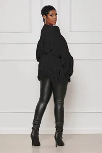 Close-up of black fringe knit cardigan showing tassel detail and texture
