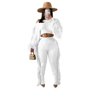 Close-up of white knitted crop top and pants set featuring bohemian fringe details