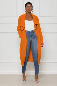 Full body view of an orange long knit cardigan sweater paired with denim jeans.