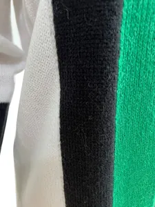 Close-up detail showing the soft handmade knit texture of the white, black, and green sweater