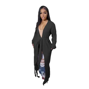 Detailed view of women's long black waffle-knit cardigan featuring fringe hem and waist tie