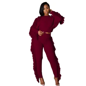 Detail of wine red knitted two-piece set featuring long sleeves and tassel fringe accents