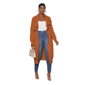 Full view of a woman styling an orange long-line knit cardigan with casual blue jeans.